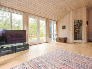 A spacious room with a large TV, a colorful rug, and a wooden ceiling. - 4 Star Holiday Home in Albaek (Aalbaek)