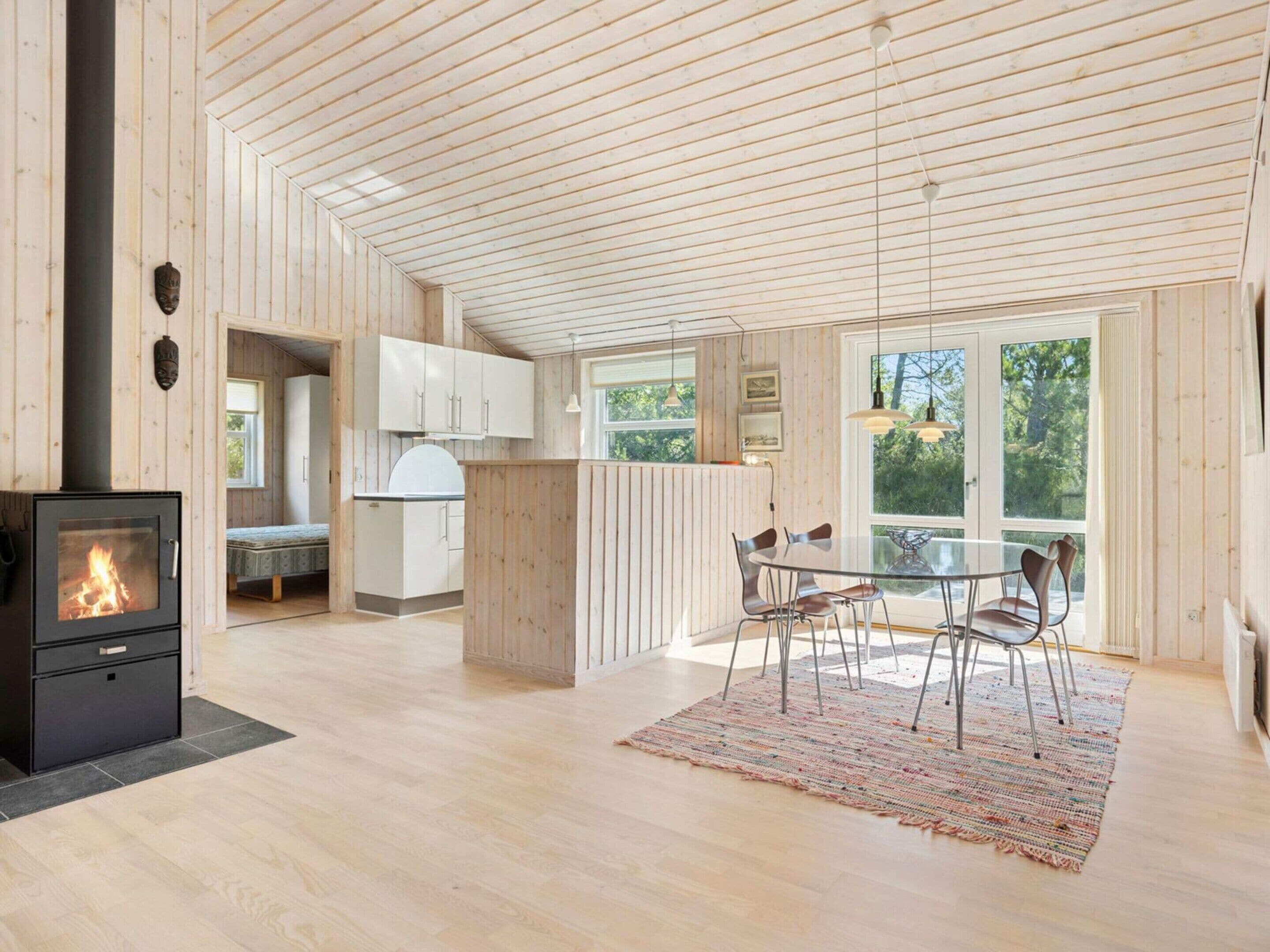 A modern kitchen with a central island, a dining area with chairs, and a large window providing a view of the outdoors.
