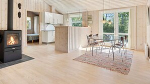 A modern kitchen with a central island, a dining area with chairs, and a large window providing a view of the outdoors. - 4 Star Holiday Home in Albaek (Aalbaek)