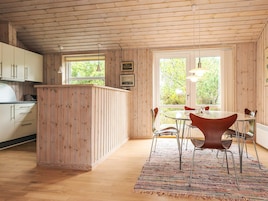 Un intérieur en bois comprenant une cuisine, un coin repas et de grandes fenêtres.