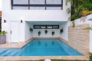 Ein Swimmingpool mit weißer Außenwand, einer Tür und einem Fenster darüber.