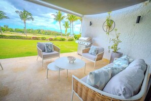 A patio area with wicker furniture, a grill, and a view of a green landscape. - Luxury on the ocean, Teeth of the Dog Golf view (La Romana,)