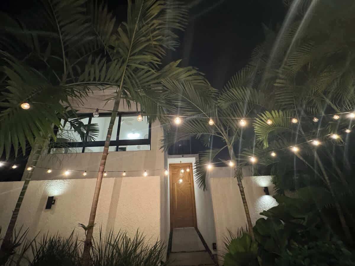 Un bâtiment moderne avec une porte en bois et des guirlandes lumineuses.