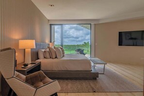Quarto moderno com uma cama grande, escrivaninha, cadeira e televisão.