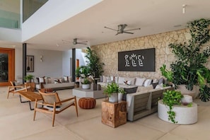 Un salon moderne avec un mur en pierre, un ensemble de canapés, des meubles en bois et des plantes en pot.