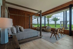 A modern bedroom with a large bed, a sofa, and a view of a lush landscape. - Villa Azurre — A New Standard of Luxury (La Romana,)