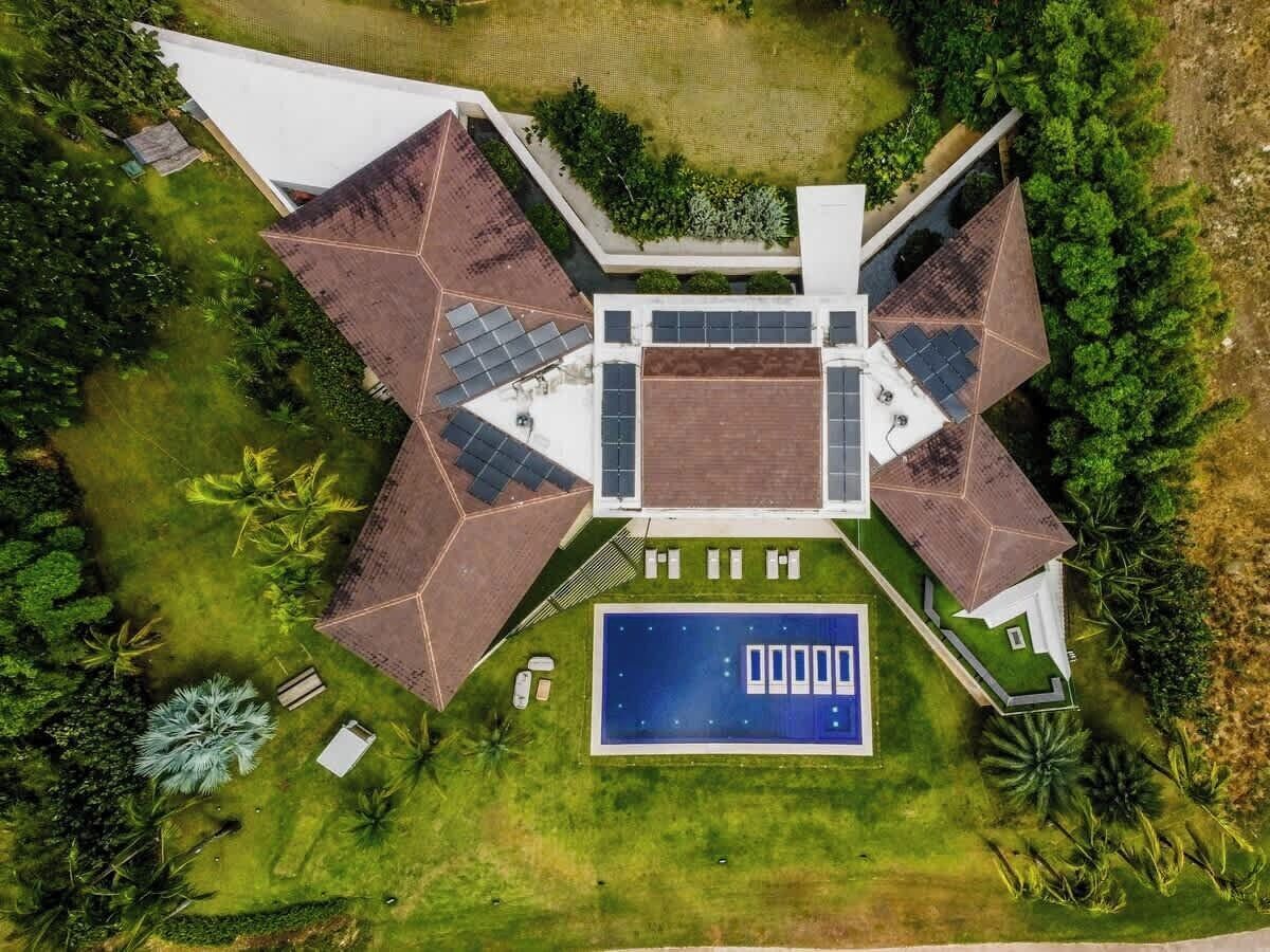 Un bâtiment moderne doté d’une piscine centrale, entouré d’une pelouse bien entretenue et d’arbres.