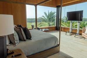 Quarto com uma cama grande, televisão e vista para a paisagem.