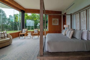 A bedroom with a large bed, a sitting area with chairs, and a view of the outdoors. - Villa Azurre — A New Standard of Luxury (La Romana,)