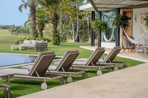 A poolside area with lounge chairs, a hammock, and a view of a tropical landscape. - Villa Azurre — A New Standard of Luxury (La Romana,)