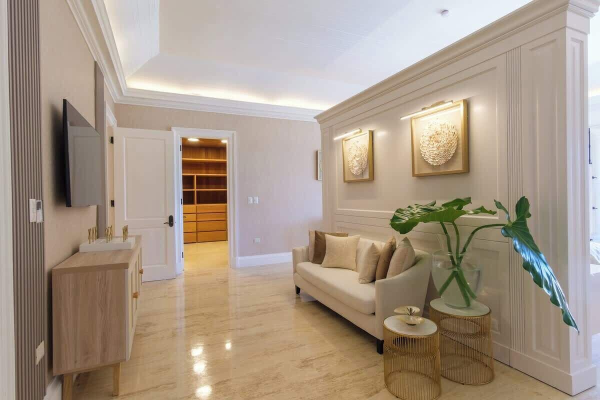 A modern living room with a sofa, a TV mounted on the wall, and a large plant.