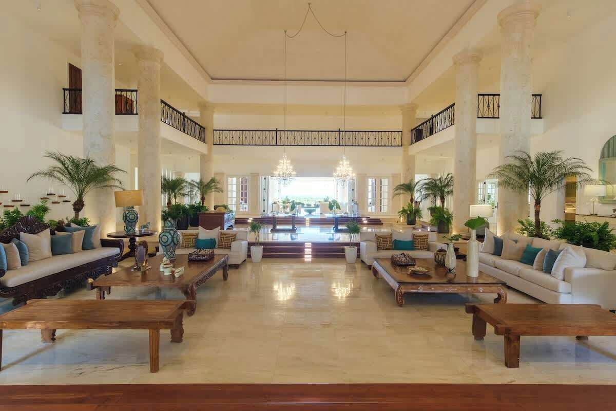 A spacious lobby with high ceilings, large columns, and a central staircase leading to upper floors.