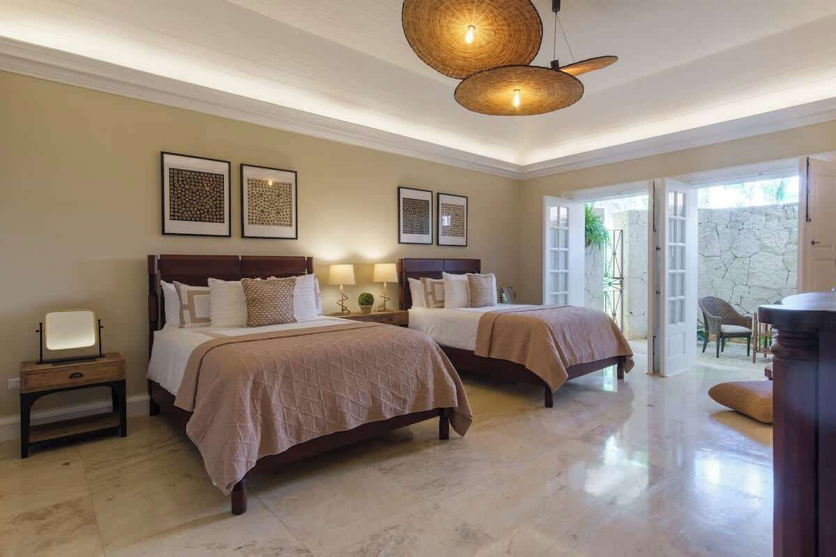 A hotel room with two beds, a sitting area, and a view of the outdoors.