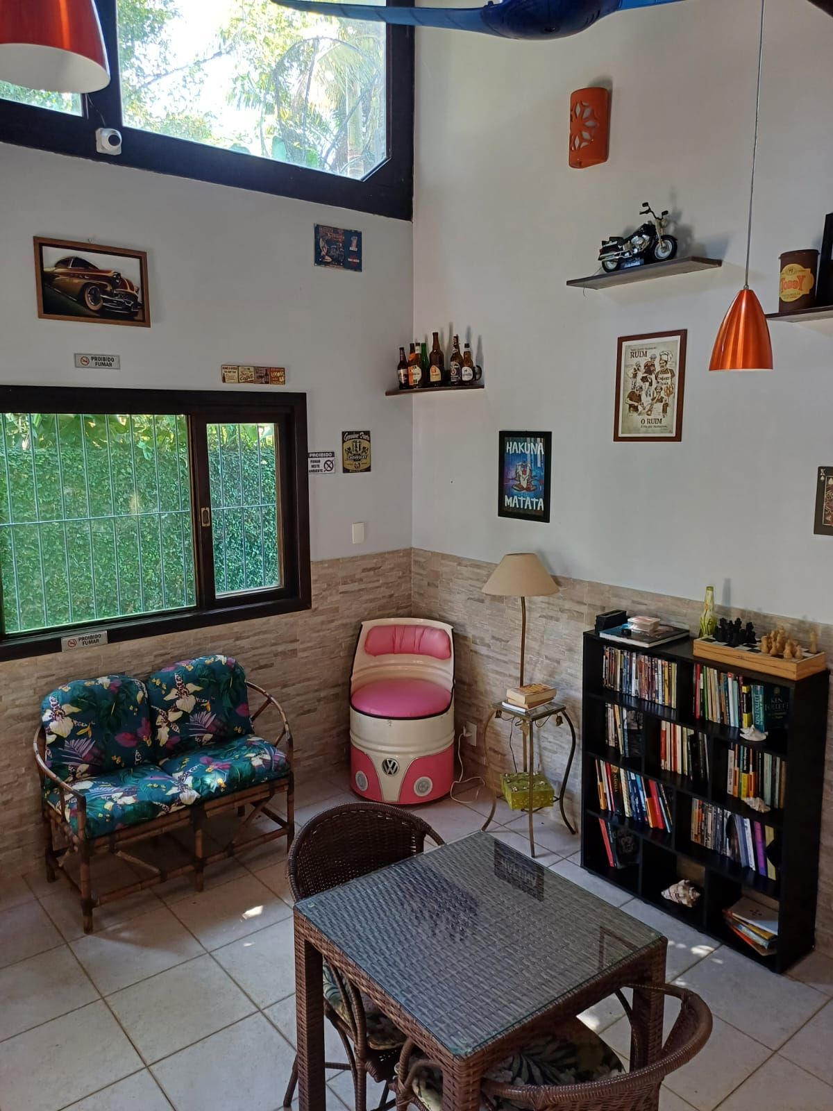 A room with a sofa, a small table, a bookshelf, and a window with a view of greenery.