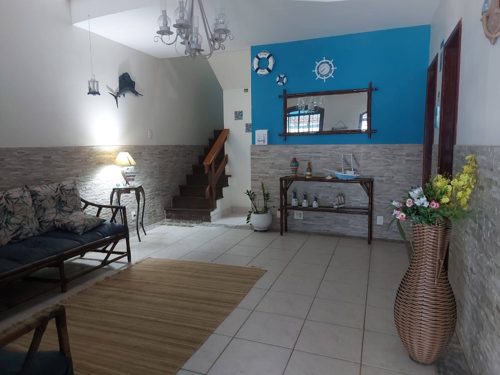 A living room with a sofa, a coffee table, a rug, a staircase, and a wall with nautical decorations.