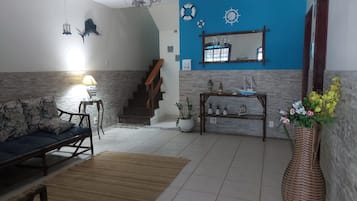 A living room with a sofa, a coffee table, a rug, a staircase, and a wall with nautical decorations.
