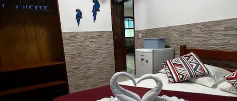 A hotel room with a bed, a TV, a fan, and a wall with decorative fish.