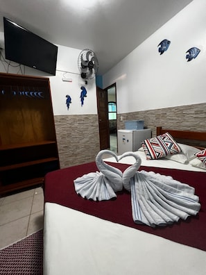 A hotel room with a bed, a TV, a fan, and a wall with decorative fish. - Azul del Mar (Ilha Grande)