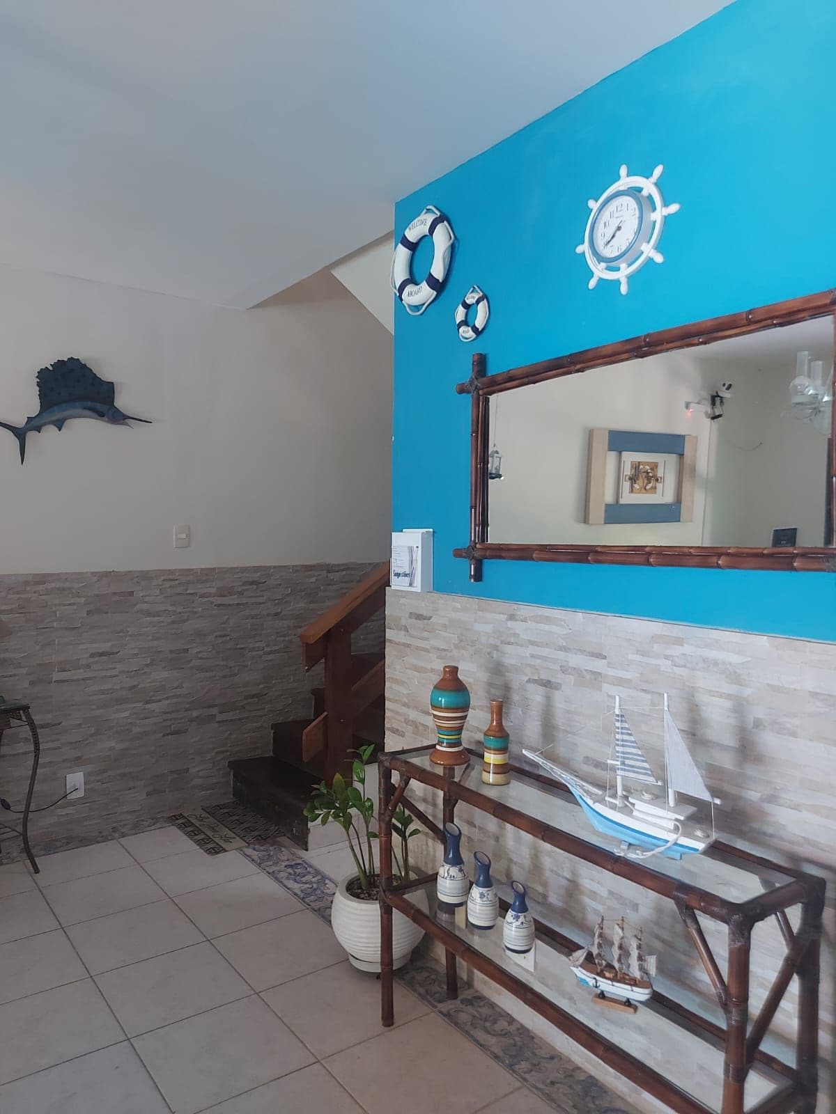 A bathroom with a blue accent wall, a wooden vanity, a mirror, and a ship decoration.