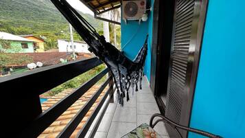 Un balcón con una hamaca, una silla y vistas a la montaña.
