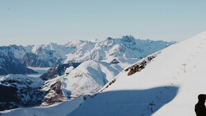 Eine verschneite Berglandschaft mit Skipisten und einer Seilbahn.