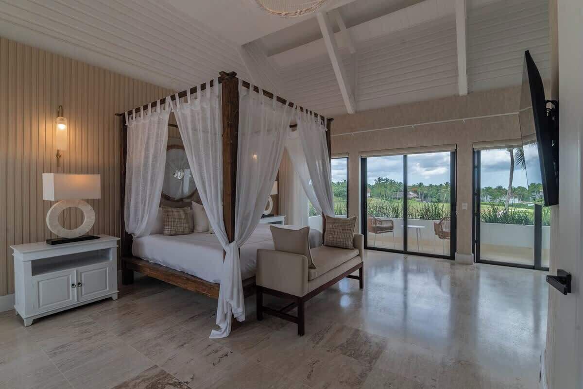 A spacious bedroom with a canopy bed, a bedside table, and a view of the outdoors.