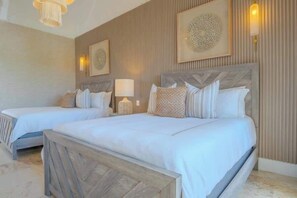 A hotel room with two beds, a wooden headboard, a wall-mounted lamp, and a patterned wall decoration. - Villa Cinco Ríos · Infinity Pool, Golf & Ocean Views, Staff Included (La Romana)