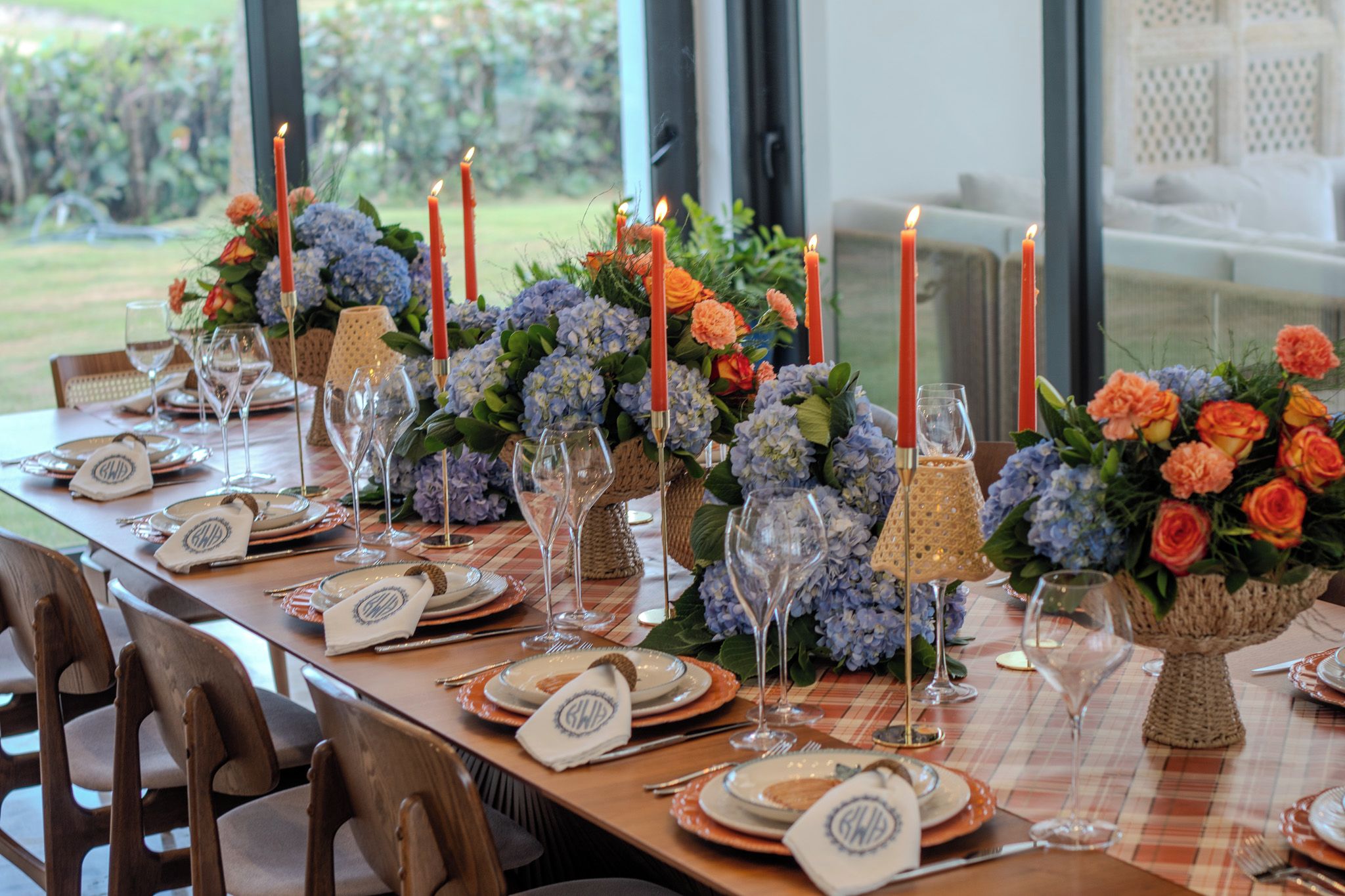A table set for a meal with candles, glassware, and floral centerpieces.