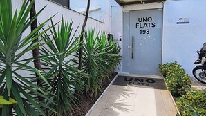 A gated entrance with a sign reading 'UNO FLATS 198' and a motorcycle parked outside. - Flats Uno - By EasyHost (João Pessoa)