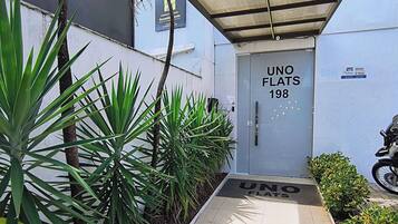 A gated entrance with a sign reading 'UNO FLATS 198' and a motorcycle parked outside.