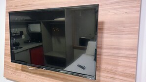 A flat-screen TV mounted on a wall with a wooden panel design. - Flats Uno - By EasyHost (João Pessoa)