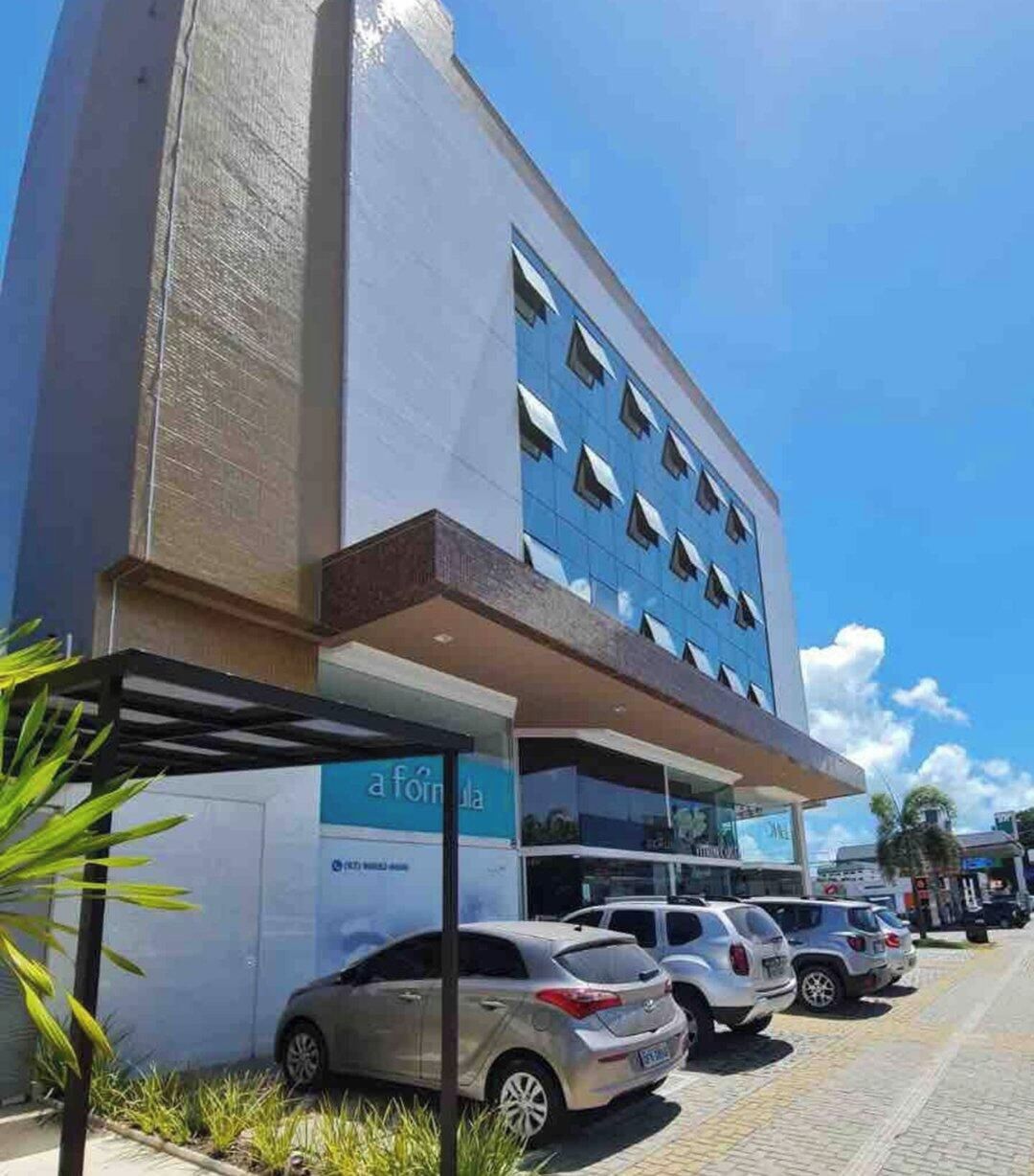 A modern building with a parking lot and a row of parked cars.