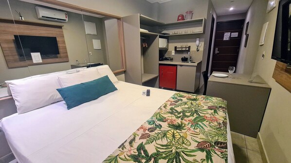 Une chambre d’hôtel comprenant un lit, un bureau, une kitchenette et une salle de bain.