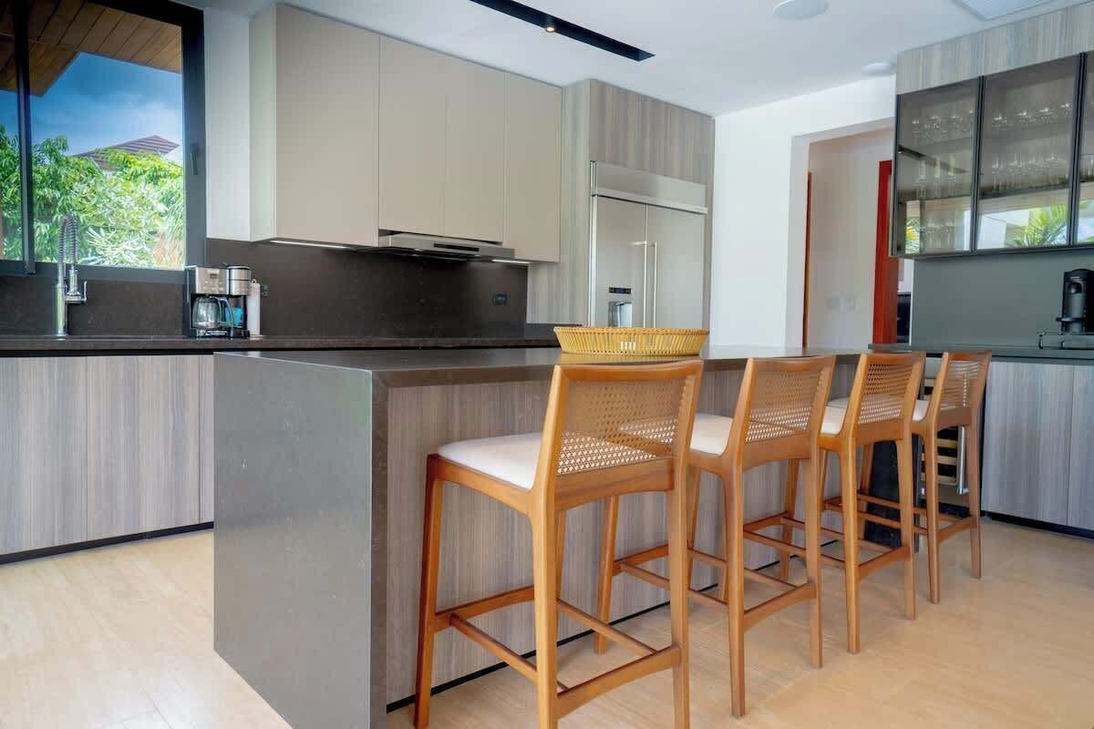 A modern kitchen with a central island, bar stools, and a refrigerator.