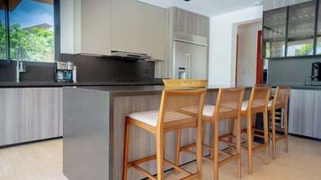 A modern kitchen with a central island, bar stools, and a refrigerator.