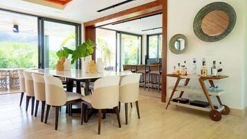 A dining area with a round table, chairs, and a bar cart with bottles.
