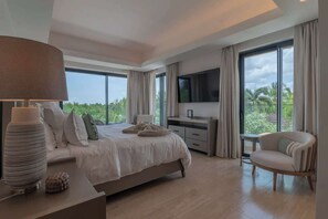 A modern bedroom with a bed, bedside table, lamp, TV, and a chair.