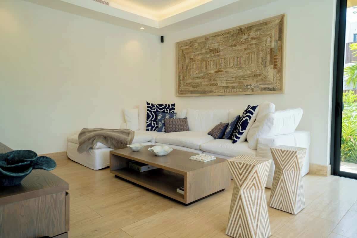 A modern living room with a white sofa, a coffee table, and decorative pillows.