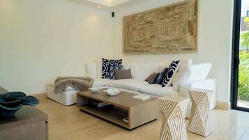 A modern living room with a white sofa, a coffee table, and decorative pillows.