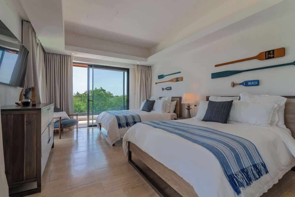 Habitación de hotel con dos camas, televisión, escritorio y vistas al exterior.