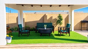 An outdoor patio with a round table, two chairs, and a sofa.
