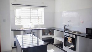 A modern kitchen with a black countertop, white walls, a window, and a built-in oven.