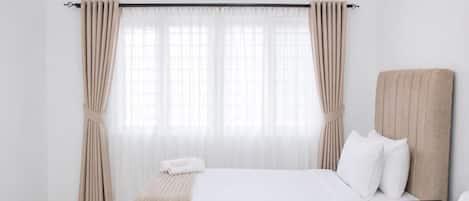 A hotel room with a bed, a bedside table, and curtains.