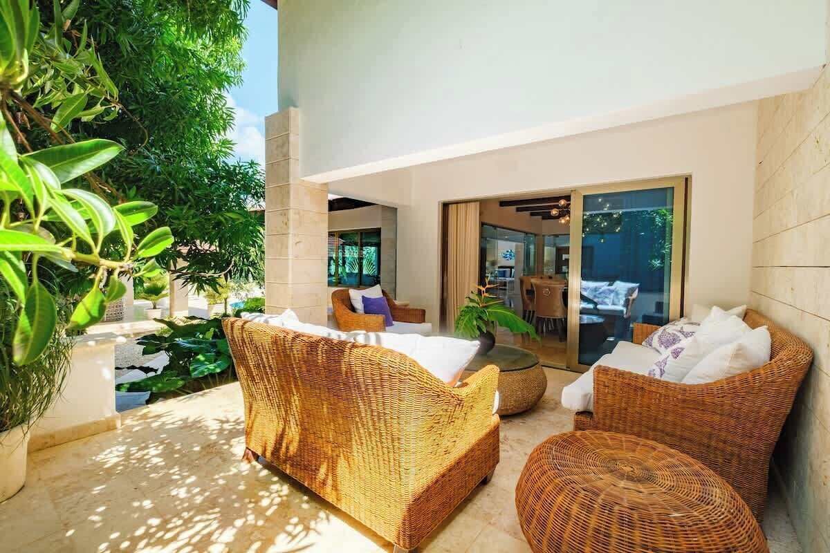 A modern outdoor seating area with wicker furniture and a glass door leading to an interior space.