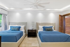 A hotel room with two beds, a ceiling fan, and a nightstand with a lamp.