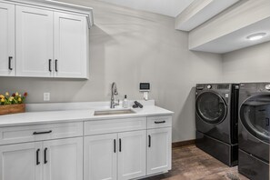 A modern kitchen with white cabinetry, a stainless steel sink, and a built-in washer and dryer.