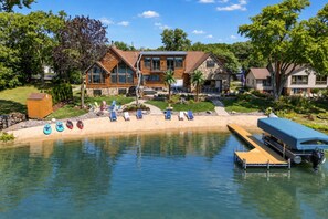 A lakeside property with a wooden cabin, a dock, and a pool area with lounge chairs.