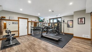 Een sportschool met trainingsapparatuur, een spiegel en een deur naar een andere ruimte.