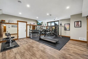A gym with exercise equipment, a mirror, and a door leading to another room.