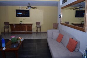A living room with a sofa, chairs, a coffee table, a TV, and a bar area. - Estancia Vacacional 20 Aguas (Ursulo Galvan)